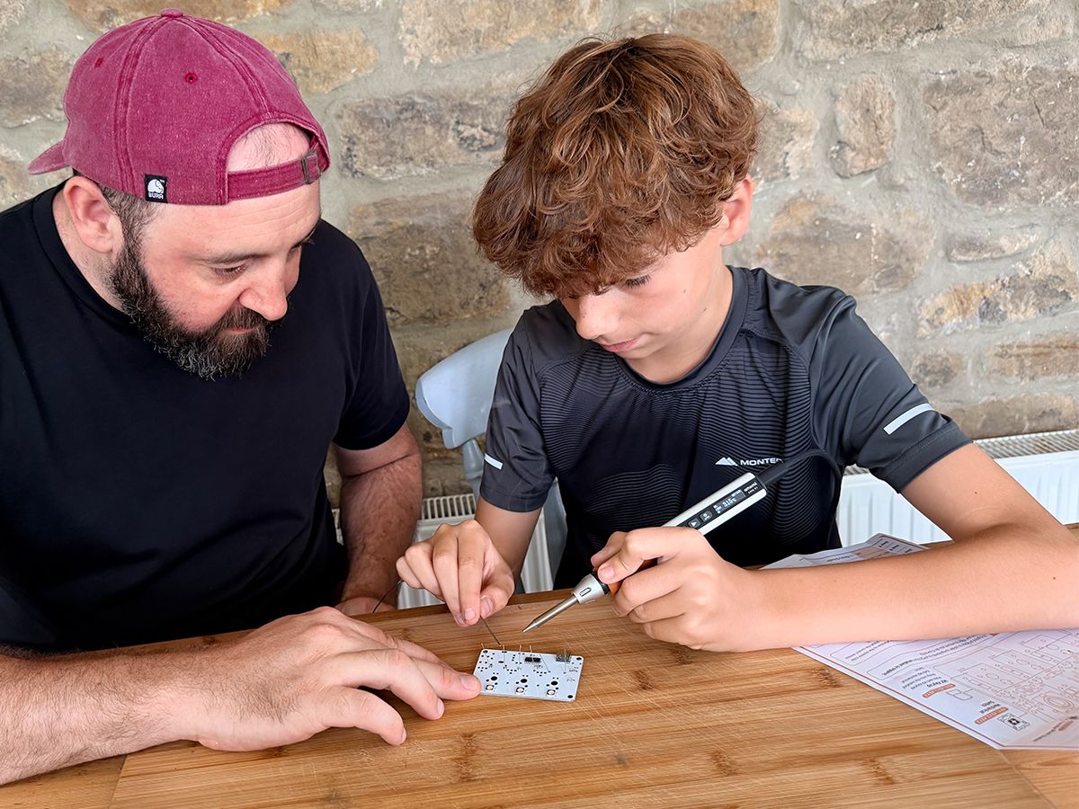 A high school student soldering with a teacher