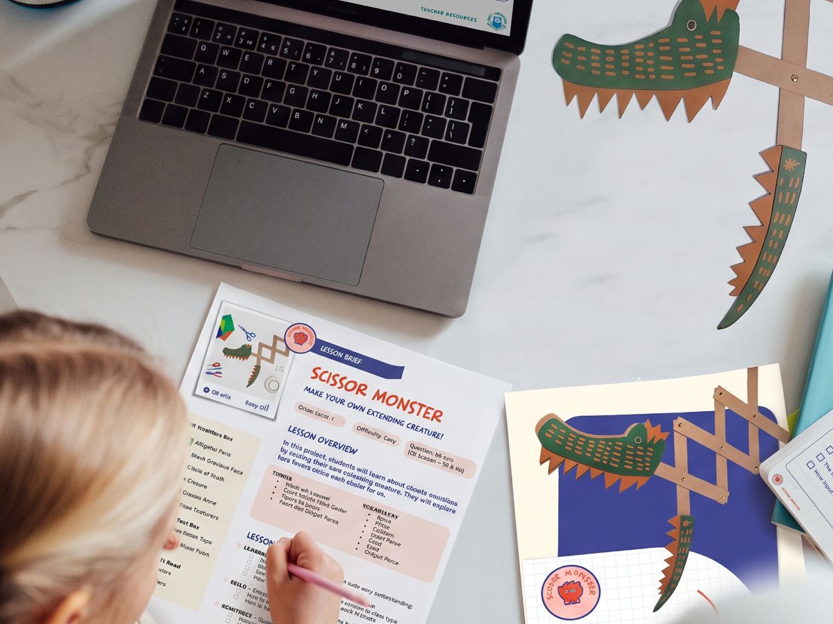 A student filling in a Scissor Monster lesson sheet beside a laptop